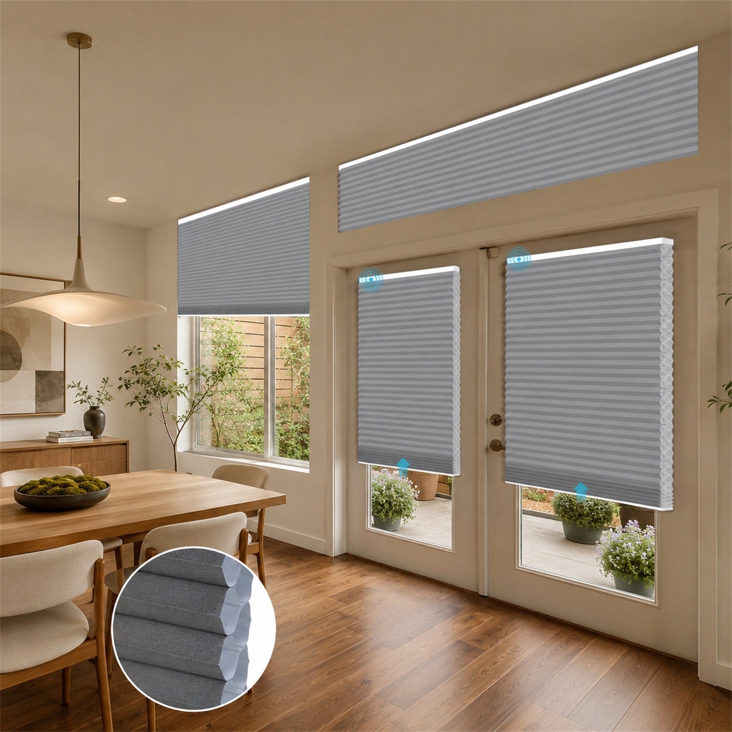 Gray cellular window and door blinds installed in a modern dining room and patio area, with an inset circular detail of the fabric texture.