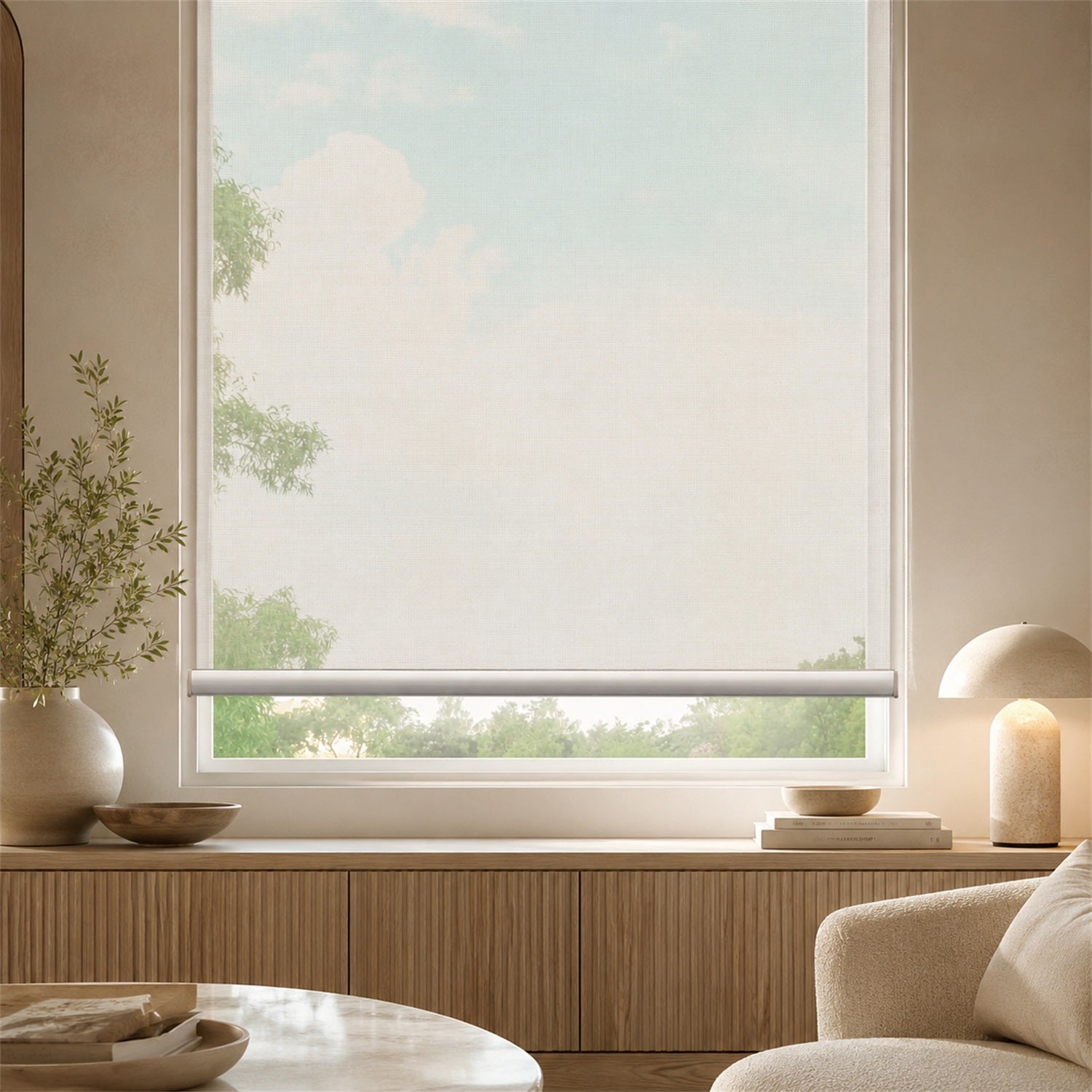A light beige roller blind partially drawn over a large window in a modern, minimalist room with warm wood paneling, a table lamp, and a neutral chair.
