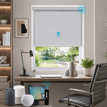 A smart home office scene featuring a light gray roller blind on a window, with a blue upward arrow graphic indicating automation. The room includes a wooden desk, black office chair, smart speakers, and a tablet.